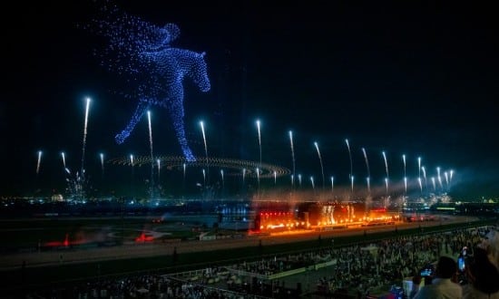 Un fantino a cavallo che corre ricreato con droni luminosi nel cielo notturno sopra all'ippodromo di Meydan per il Dubai World Cup